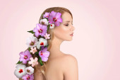 Hezká žena na sobě krásné věnec z květin na světle růžovém pozadí