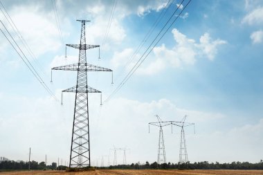 Güneşli bir günde elektrik iletim hatları olan yüksek voltaj kuleleri.