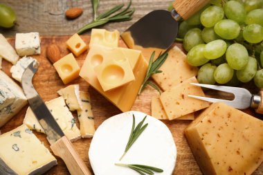 Düz kompozisyon, farklı peynir çeşitleri ve bıçaklarla ahşap masanın üzerinde duruyordu.