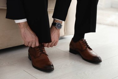 Damat şık bir düğün ayakkabısı giyiyor, kapalı bir yerde, yakın plan.