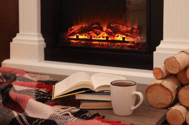 Şöminenin yanında bir fincan sıcak çay ve kitaplar. Sıcak atmosfer