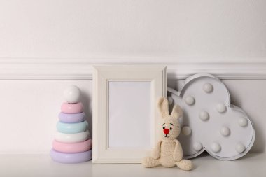 Boş fotoğraf çerçevesi, duvarın yanında sevimli oyuncaklar ve dekor, mesaj için yer. Bebek odasının iç mekanı