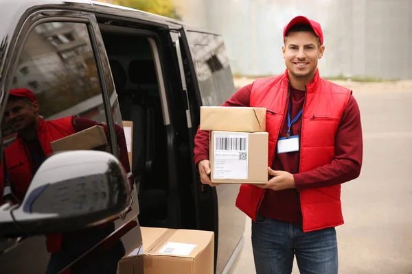 Courier with parcels near delivery van outdoors