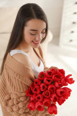 Evinde kırmızı lale buketi olan mutlu bir kadın. 8 Mart kutlamaları