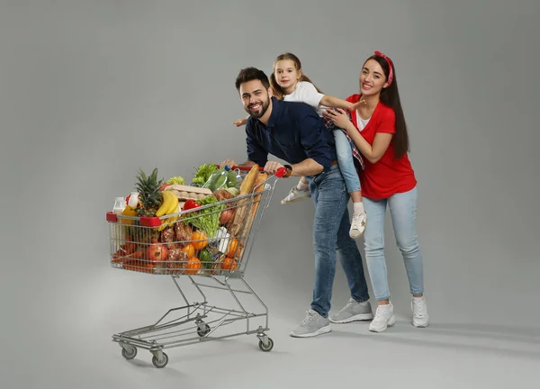 Gri Arka Planda Alışveriş Arabalarıyla Dolu Mutlu Bir Aile — Stok fotoğraf
