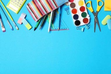 Açık mavi arkaplanda farklı kırtasiye malzemesi, metin için boş alanı olan düz bir yer. Okula geri dön.