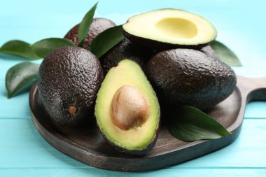 Bütünüyle tahta ve turkuaz masa üzerinde avokado kes, yakın plan.