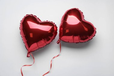 Kırmızı kalp şeklinde balonlar beyaz arka planda, düz yerde. Sevgililer Günü kutlaması