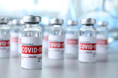 Işık masasının üzerinde COVID-19 aşısı olan cam şişeler.