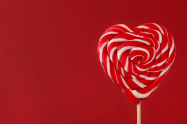 Kırmızı arka planda tatlı kalp şeklinde lolipop, metin için yeri olan yakın çekim görüntüsü. Sevgililer Günü kutlaması
