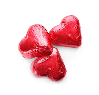 Kalp şeklinde çikolata şekerlemeleri kırmızı folyoyla beyaz arka planda, üst görünümde.