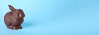 Açık mavi arkaplanda çikolatalı Paskalya tavşanı, metin için boşluk