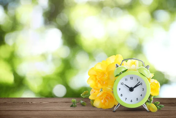 木製のテーブルの上に目覚まし時計と春の花 テキストのためのスペース 時間の変化 — ストック写真