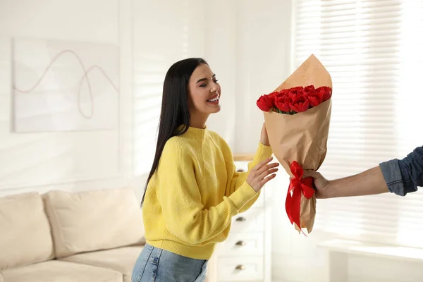 快乐的女人在家里收到男人送的红色郁金香花 三月八日庆祝活动 — 图库照片