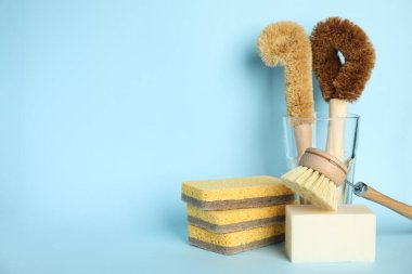 Açık mavi arkaplanda temizlik araçları, metin için boşluk. Bulaşık malzemeleri.