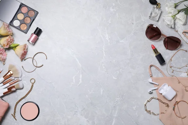 Flat lay composition with makeup products and accessories on light grey marble background. Space for text