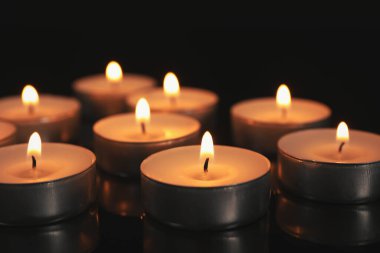 Karanlıkta siyah masada yanan mumlar.