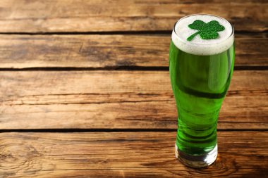 Bir bardak yeşil bira ve ahşap masa üzerinde yonca yaprağı, yazı için yer. Aziz Patrick Günü kutlaması