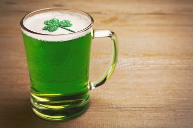 Bir bardak yeşil bira ve ahşap masa üzerinde yonca yaprağı, yazı için yer. Aziz Patrick Günü kutlaması