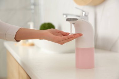 Banyoda otomatik sabun makinesi kullanan kadın, yakın plan.