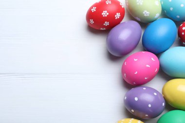 Beyaz ahşap masaya parlak boyanmış yumurtalar, yazı için yeri olan düz bir yer. Mutlu Paskalyalar