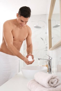 Banyoda tıraş köpüğü olan yakışıklı bir adam.