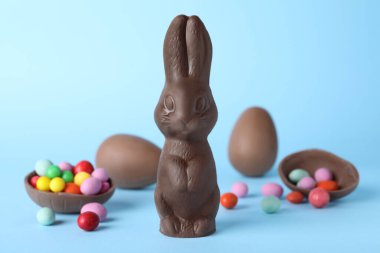 Çikolatalı Paskalya tavşanı ve açık mavi arka planda yumurtalar.