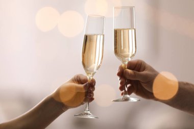 İnsanlar arka planda bulanık bir şekilde şampanya bardaklarını tokuşturuyor. Yakın plan. Bokeh etkisi