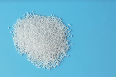 Açık mavi arkaplandaki amonyum nitrat tanecikleri, metin için yeri olan düz yataklar. Mineral gübresi