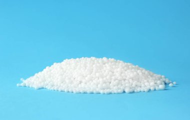 Açık mavi arkaplanda amonyum nitrat peletleri, metin için boşluk. Mineral gübresi
