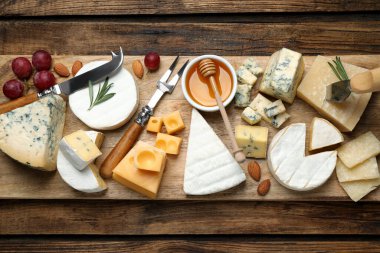 Düz kompozisyon, farklı peynir çeşitleri ve bıçaklarla ahşap masanın üzerinde duruyordu.