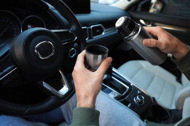 Termoslu bir adam sürücü koltuğunda, yakın plan.