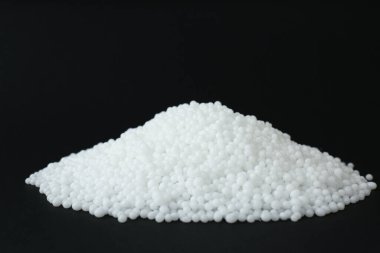 Siyah arkaplandaki amonyum nitrat tanecikleri, metin için boşluk. Mineral gübresi