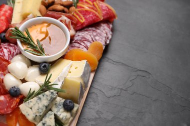 Siyah masanın üstünde farklı lezzetli atıştırmalıklar bulunan ahşap tabaklar. Metin için boşluk