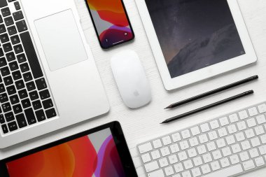 MYKOLAIV, UKRAINE - 28 Ağustos 2020: Beyaz masa üzerinde iPhone 11, MacBook laptop ve iPad tabletleri ile düz kompozisyon