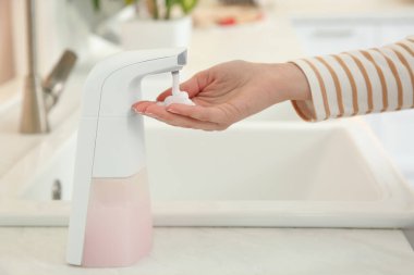 Mutfakta otomatik sabun makinesi kullanan kadın, yakın plan.