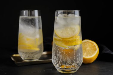 Limon dilimli soda ve siyah masada buz.