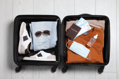 İçinde pasaport, bilet, dezenfektan ve koruyucu maske olan bavulu aç. Karantina sırasında seyahat