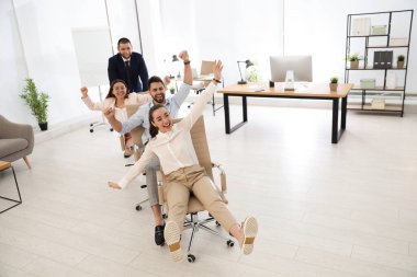 Mutlu ofis çalışanları iş yerinde sandalyeye biniyor.