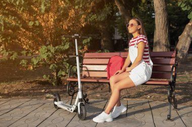 Parkta elektrikli scooter kullanan genç bir kadın.