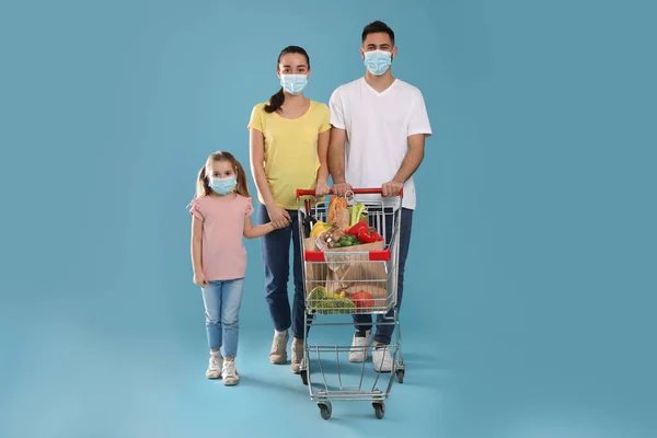 Koruyucu Maskeli Bir Aile Açık Mavi Arka Planda Yiyecek Dolu — Stok fotoğraf