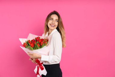 Pembe arka planda kırmızı lale buketi olan mutlu bir kadın. Mesaj için yer var. 8 Mart kutlamaları