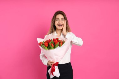 Pembe arka planda kırmızı lale buketi olan mutlu kadın. 8 Mart kutlamaları