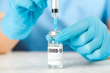 Şırıngayı Coronavirus aşısıyla dolduran doktor laboratuvar masasında, yakın plan.