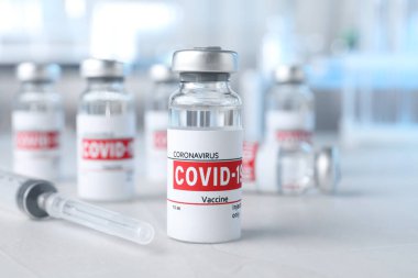 Cam şişelerde COVID-19 aşısı ve şırınga var.