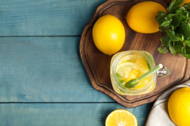 Serin, taze limonata ve açık mavi ahşap masa üzerinde meyveler. Metin için boşluk