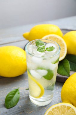Soğuk taze limonata ve gri ahşap masada meyveler.
