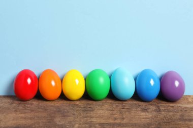 Ahşap masadaki Paskalya yumurtaları açık mavi arkaplana karşı, metin için boşluk