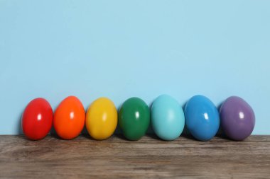 Ahşap masadaki Paskalya yumurtaları açık mavi arkaplana karşı, metin için boşluk