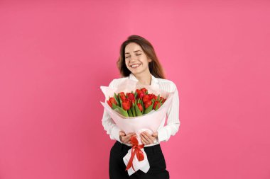 Pembe arka planda kırmızı lale buketi olan mutlu kadın. 8 Mart kutlamaları